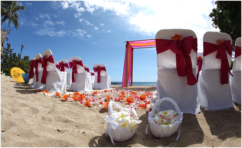 Hawaii beach wedding with dark pink sashes for the chairs with flowers form Hawaii