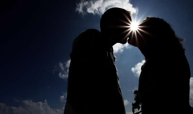 Sun shinning through the kiss of love on the beach in Hawaii for a photo tour after the wedding