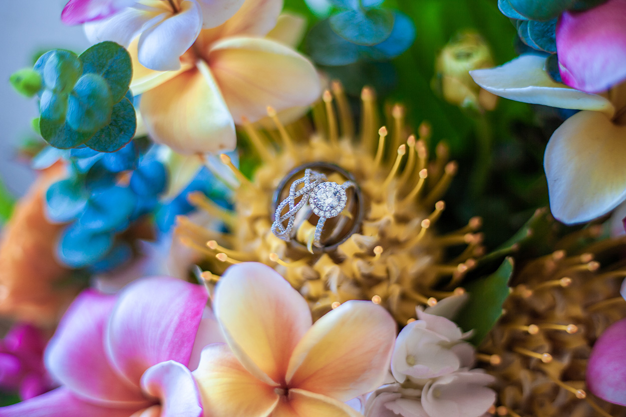 Wedding rings in a bouquet of proteas and plumeria