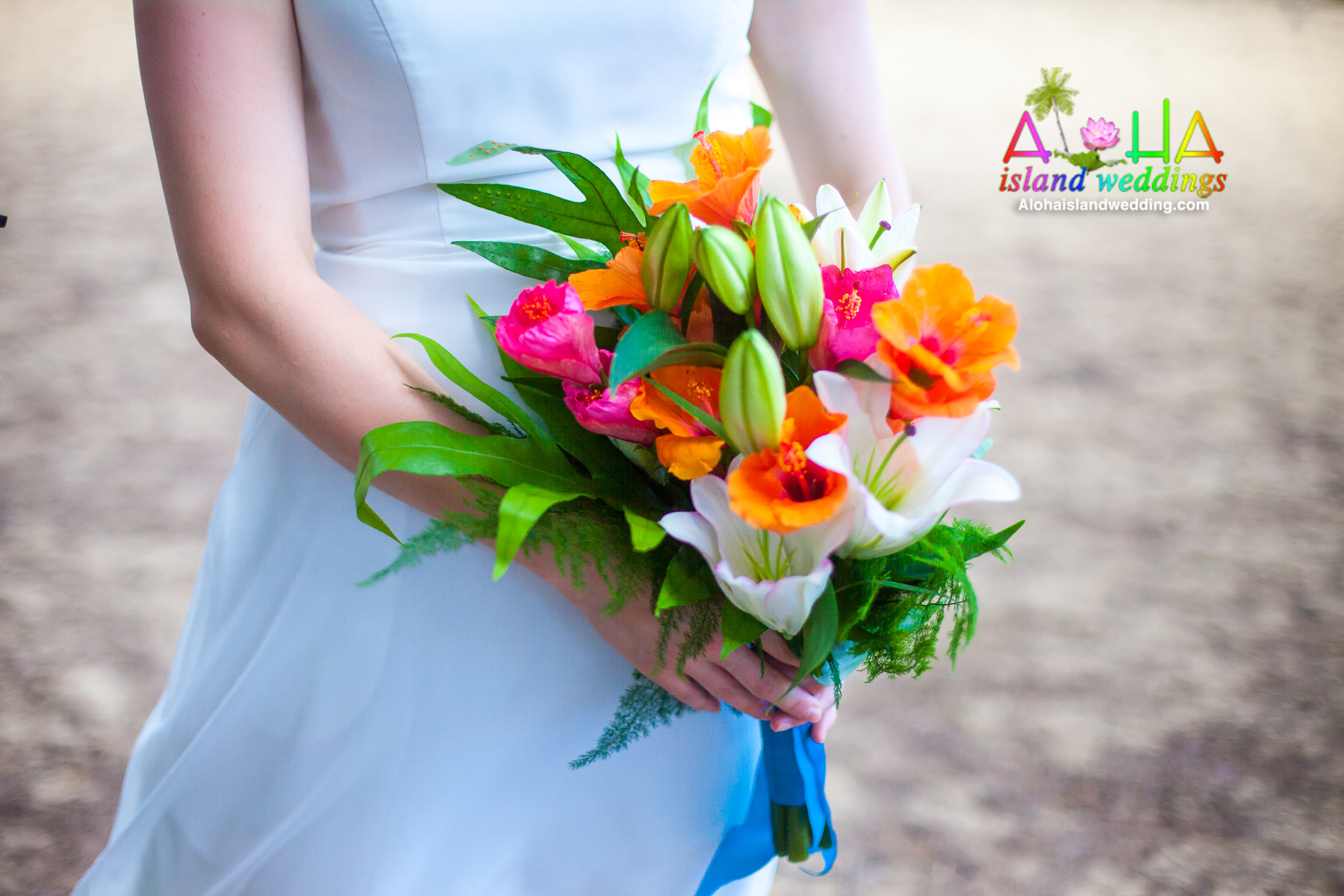 The bride holds her bouquet of white lilies and orange and red hibiscus before she walks down the aisle