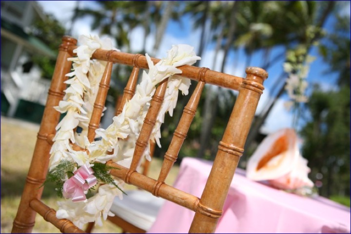 Bamboo chair with a white ginger lei and a conch shell beside a pink table