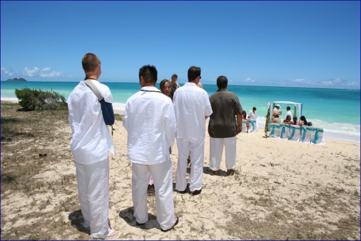 Chris and his groomsmen waiting on the sand by the arch