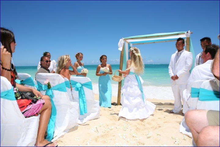 Angela walking down the aisle between chairs with turquoise sashes