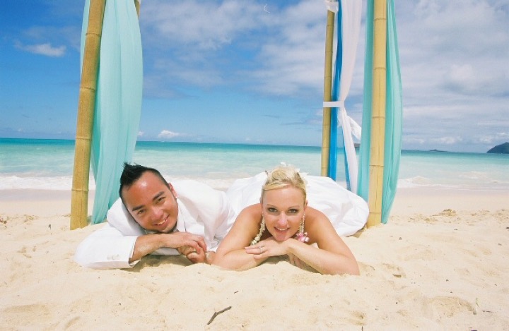 The newlyweds lying face to face on the sand