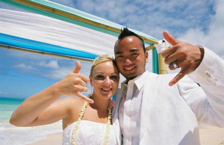 Angela and Chris making shaka signs under the arch