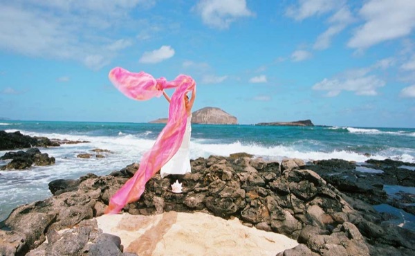 Ashley playing with rainbow chiffon on the cliffs after ceremony, smiling