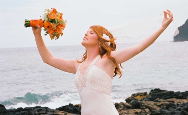 Ashley throwing her orange bouquet in the air by the sea, from another angle