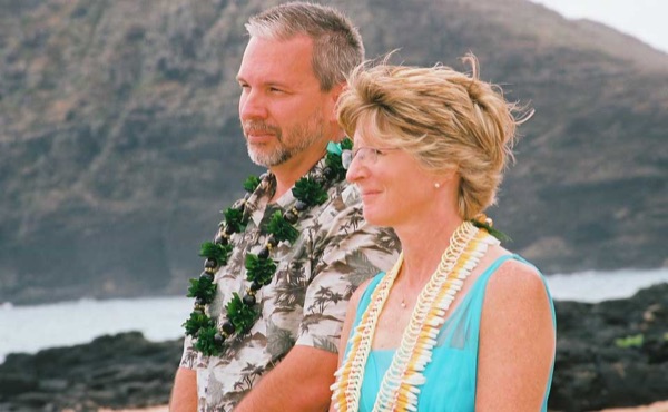 Ashley and her groom with family on the beach, from another angle