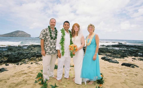 Ashley and her groom with family on the beach, smiling