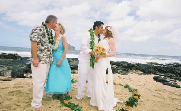 Ashley and her groom with family on the beach, in the sunshine