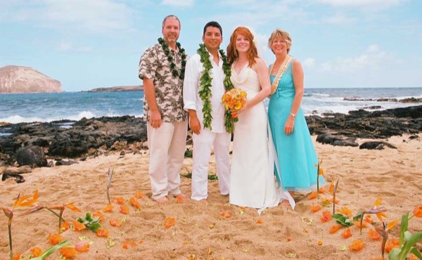 Ashley and her groom with family on the beach, laughing together