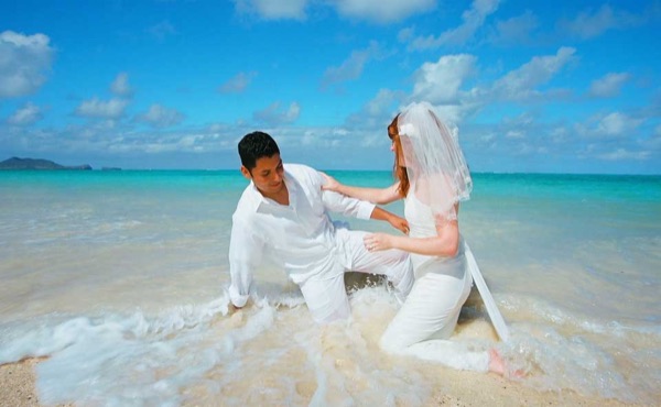 Ashley and her groom in the water at Lanikai, in the sunshine