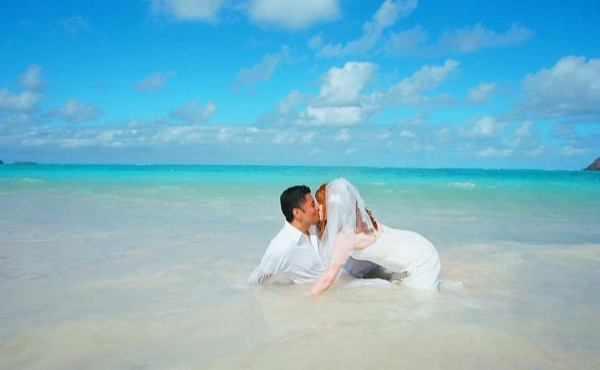 Ashley and her groom in the water at Lanikai, laughing together