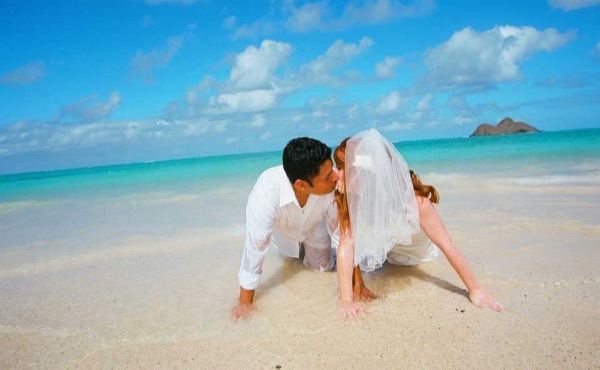 Ashley and her groom in the water at Lanikai, under a blue sky