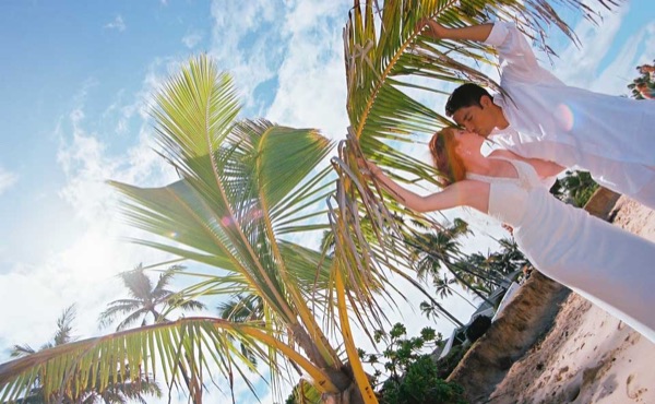 Ashley and her groom under a palm tree at Lanikai, smiling