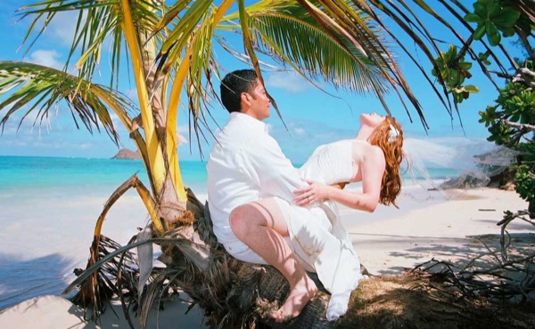 Ashley and her groom under a palm tree at Lanikai, laughing together