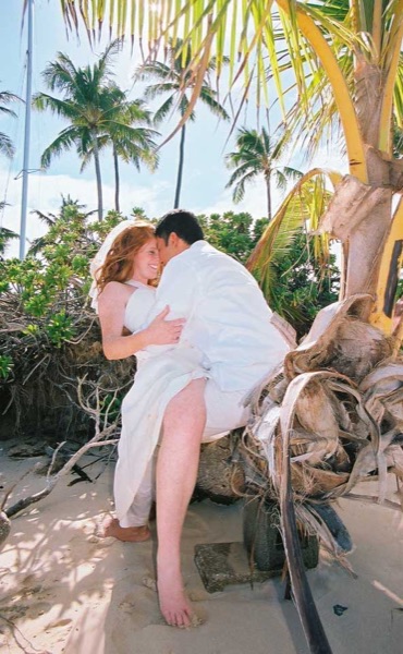 Ashley and her groom under a palm tree at Lanikai ur, under a blue sky