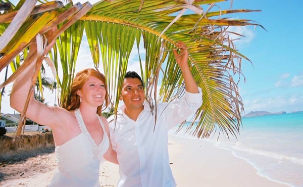 Ashley and her groom under a palm tree at Lanikai ur, smiling