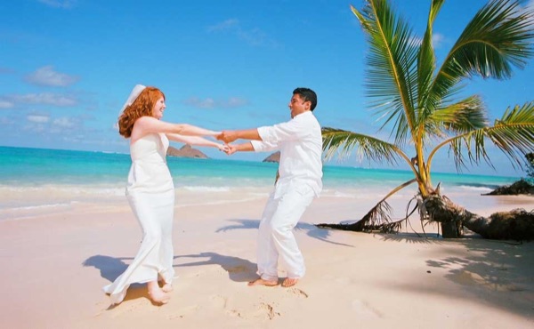 The groom twirling Ashley at Lanikai, smiling