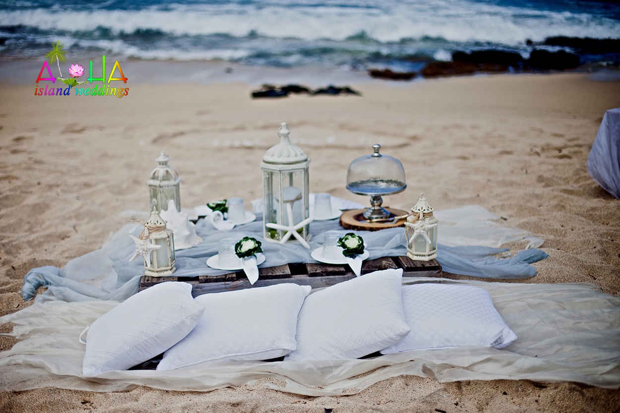 Bohemian style table on the beach with candle lanterns, starfish and a glass cake stand