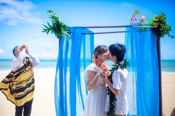 Hawaiian minister blowing the conch shell at a beach wedding