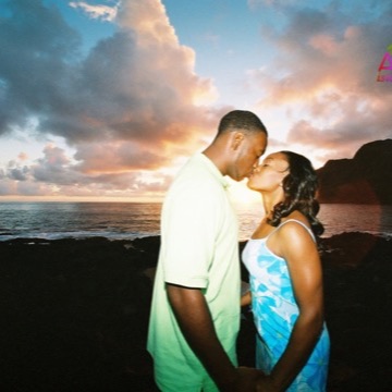 A couple kisses at sunset on the rocks at Makapuu beach