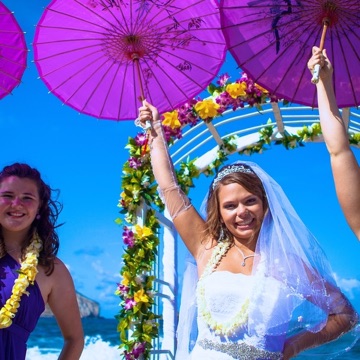 Stephanie and Ryan with pink parasols on the beach