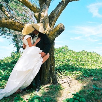 Melissa and Josh kissing by a tree on the beach