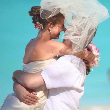 Marika and Joe embracing with her veil blowing in the wind