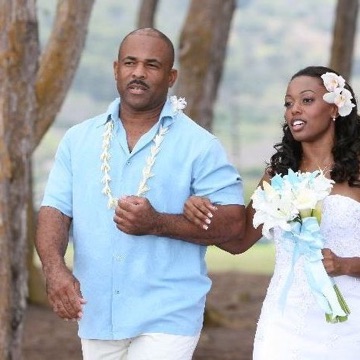 Naheshae and her groom walking under the trees at her beach wedding