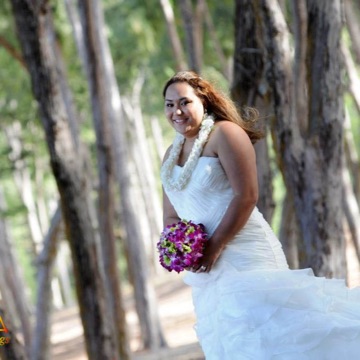 Riini in her wedding dress among the trees by the beach