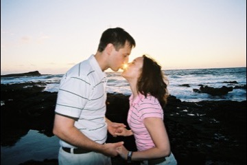 Couple sharing a kiss by the ocean at sunrise at Makapuu