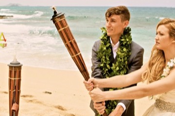 Jill and James lighting a bamboo tiki torch at their beach wedding