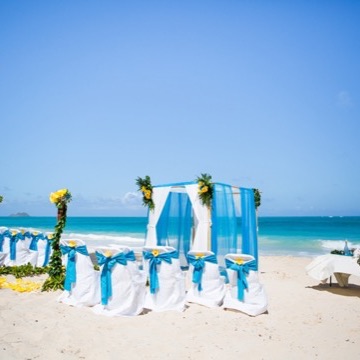 White chairs with turquoise sashes and a draped arch on Waimanalo beach