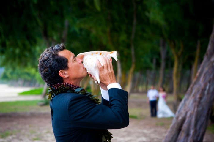 Hawaiian minister Kimo blowing the conch shell before Grace and Minh's ceremony
