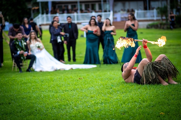 Fire knife dancer bending back with a flaming knife as the newlyweds and bridal party watch at a North Shore estate wedding