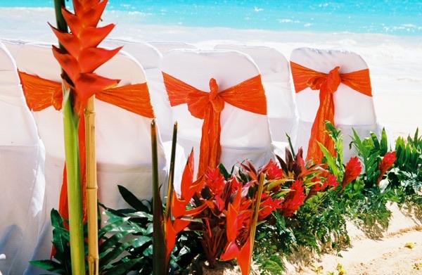 Red ginger with white chairs and orange sashes on the beach