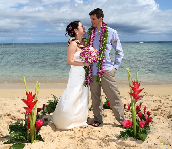 Couple standing in a circle of red Hawaiian flowers with red ginger
