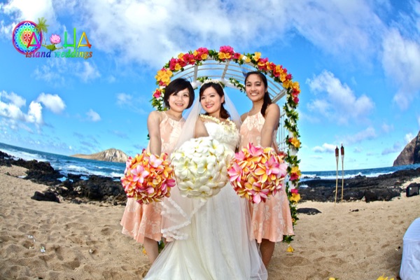 Bride with a white plumeria bouquet and bridesmaids with rainbow plumeria bouquets