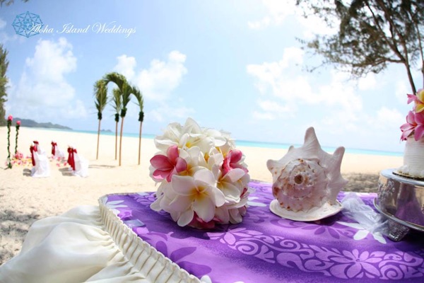 White plumeria bouquet for the maid of honor beside a conch shell and wedding cake