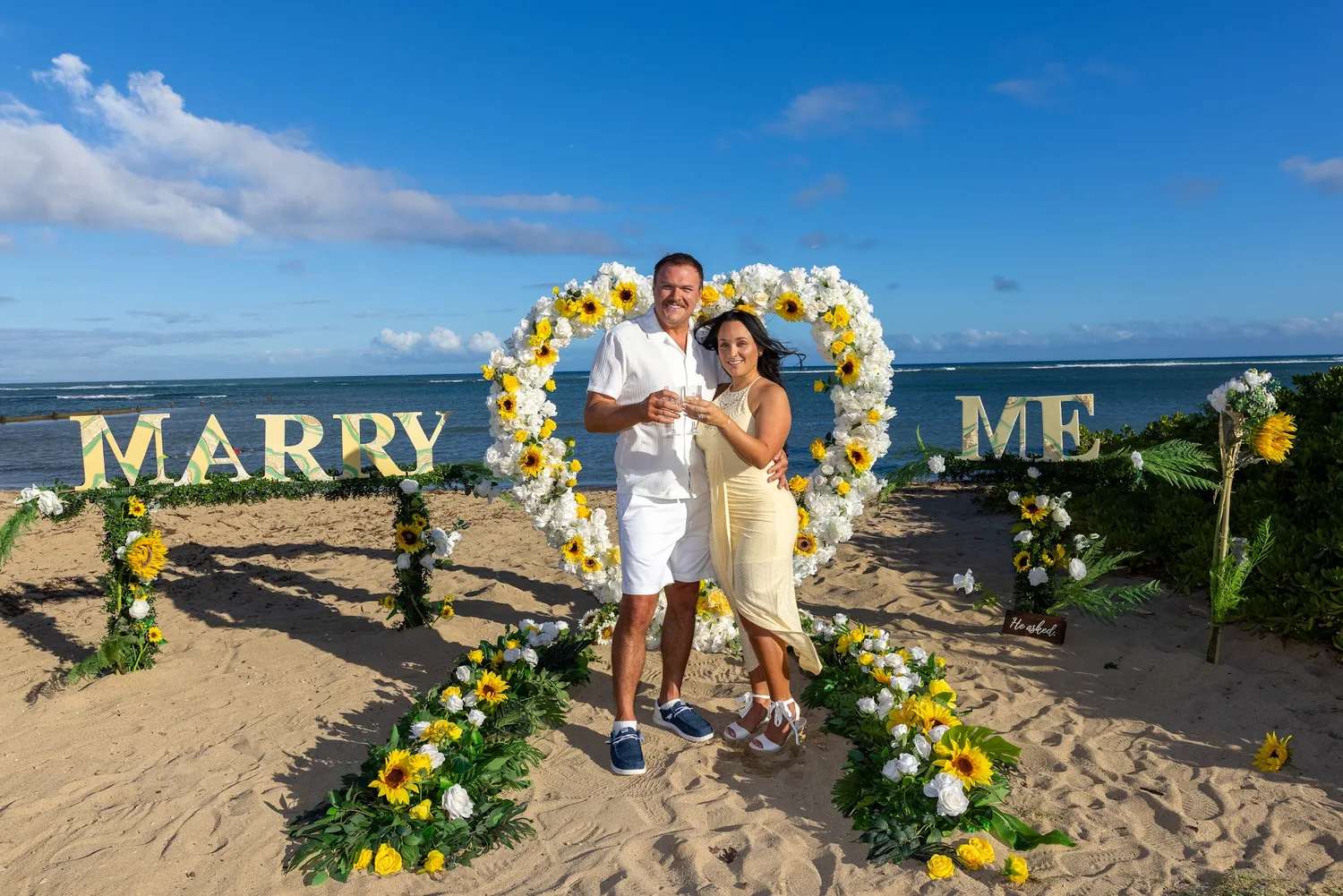 Furman and Makenzi in the flower heart between the MARRY ME letters