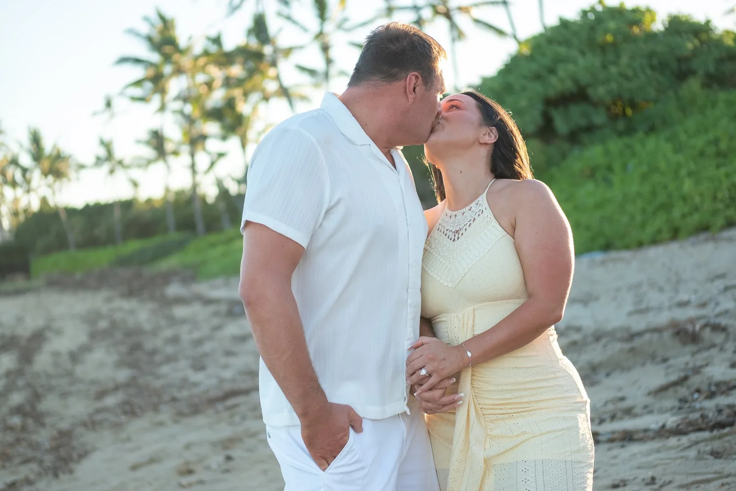 A kiss by the trees at the edge of the beach