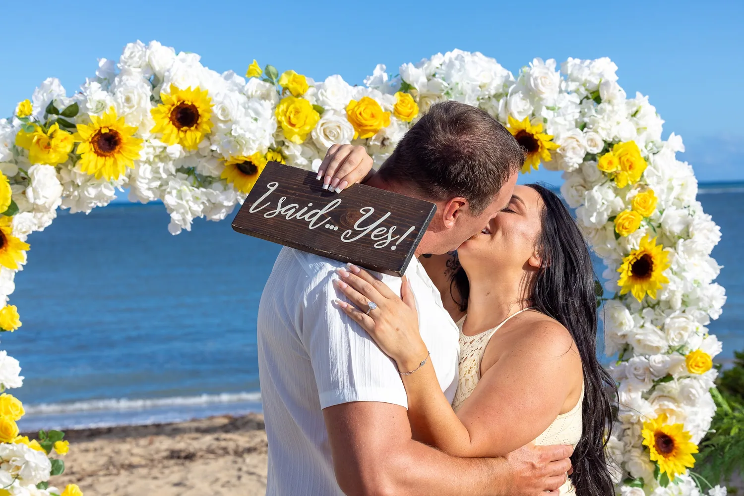 A kiss while holding their He asked and I said yes signs
