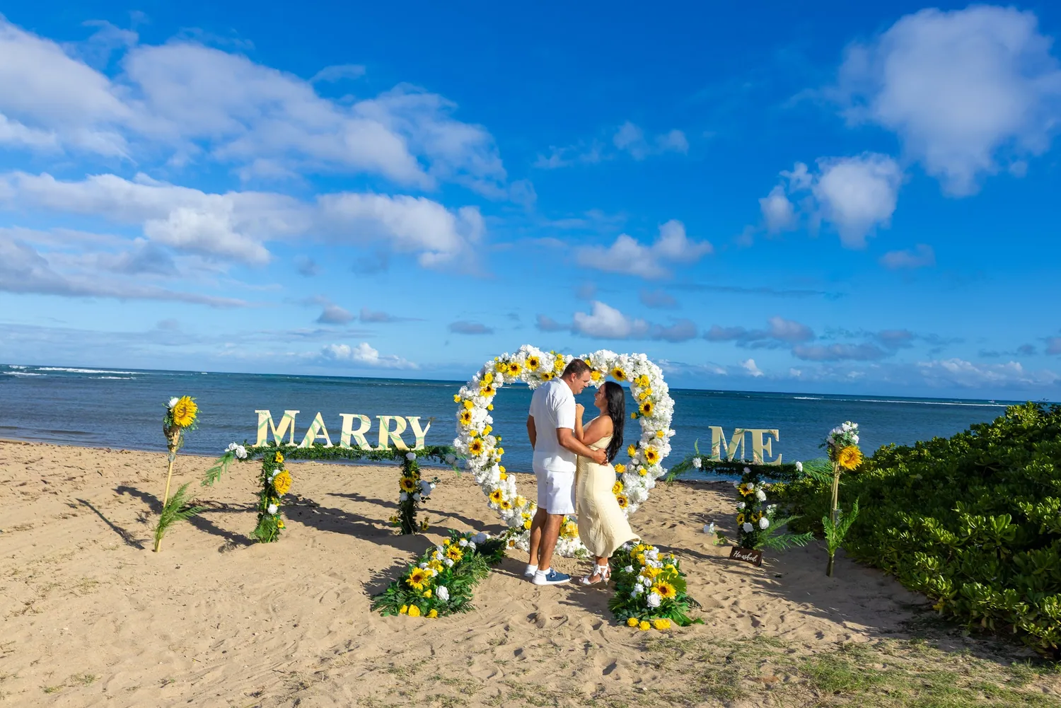 White MARRY ME letters with sunflowers beside the flower heart