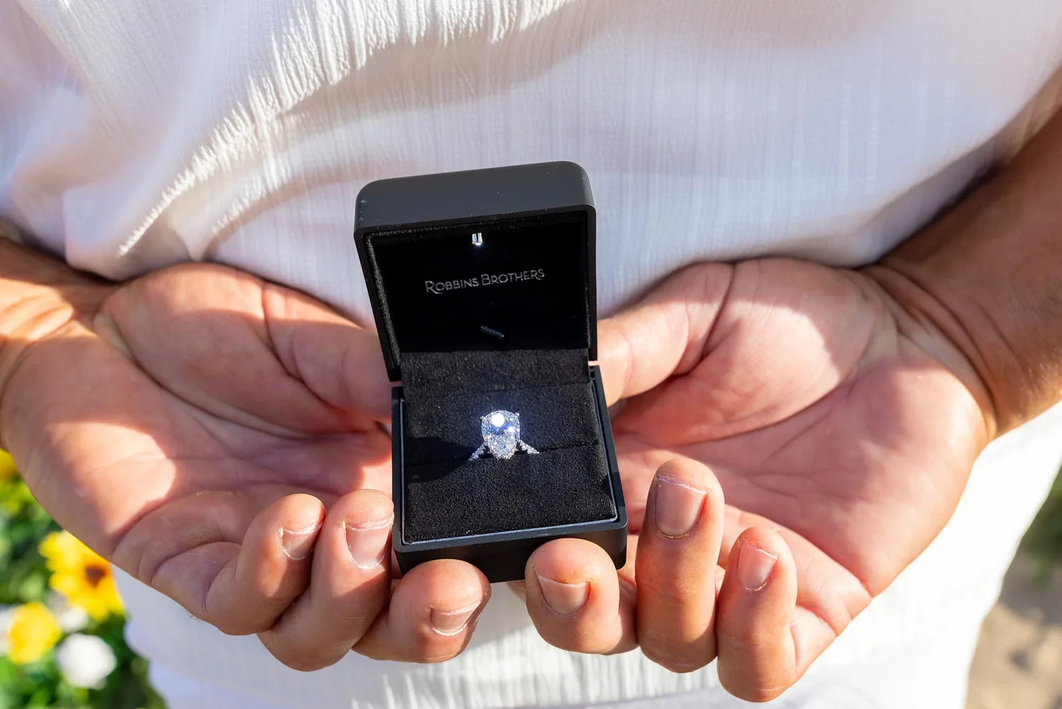 The open ring box held out in his hands