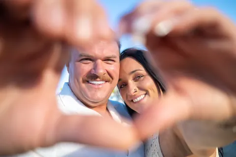 Heart hands framing them, with the ring