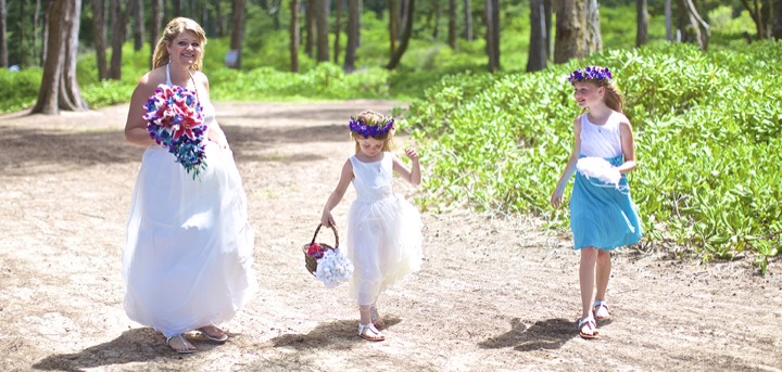 Flower girls in purple head leis walking with the bride