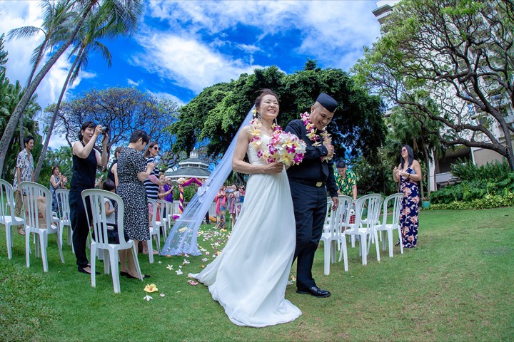 The newlyweds walking back down the aisle on the garden lawn as guests cheer