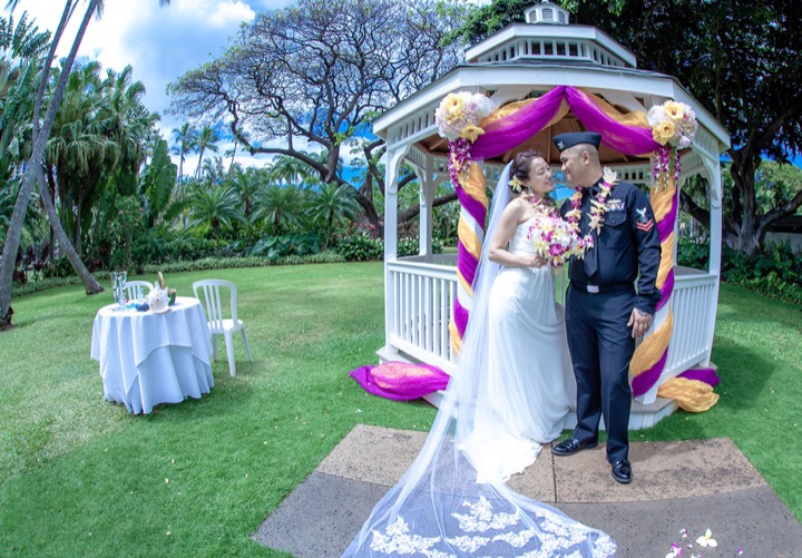 Bryan and Rie about to kiss under the white wooden gazebo decorated in pink and orange