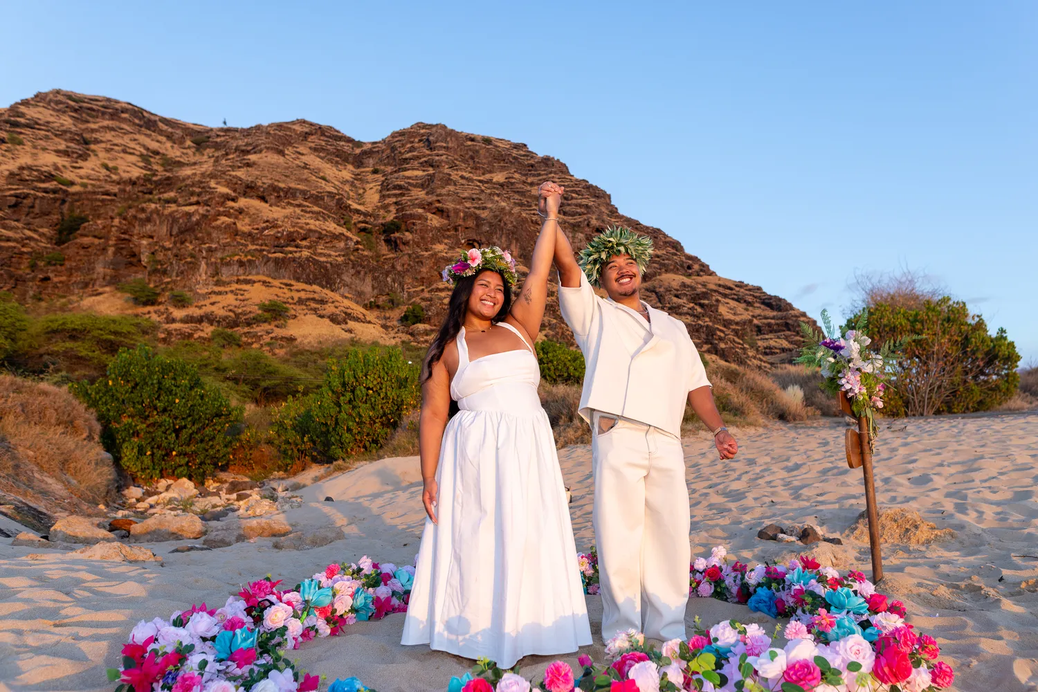 Arms raised in celebration by the flower heart, at a horseback proposal on Oahu